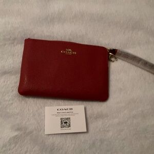 New Coach red corner zip wristlet in signature canvas comes with a Coach charm.